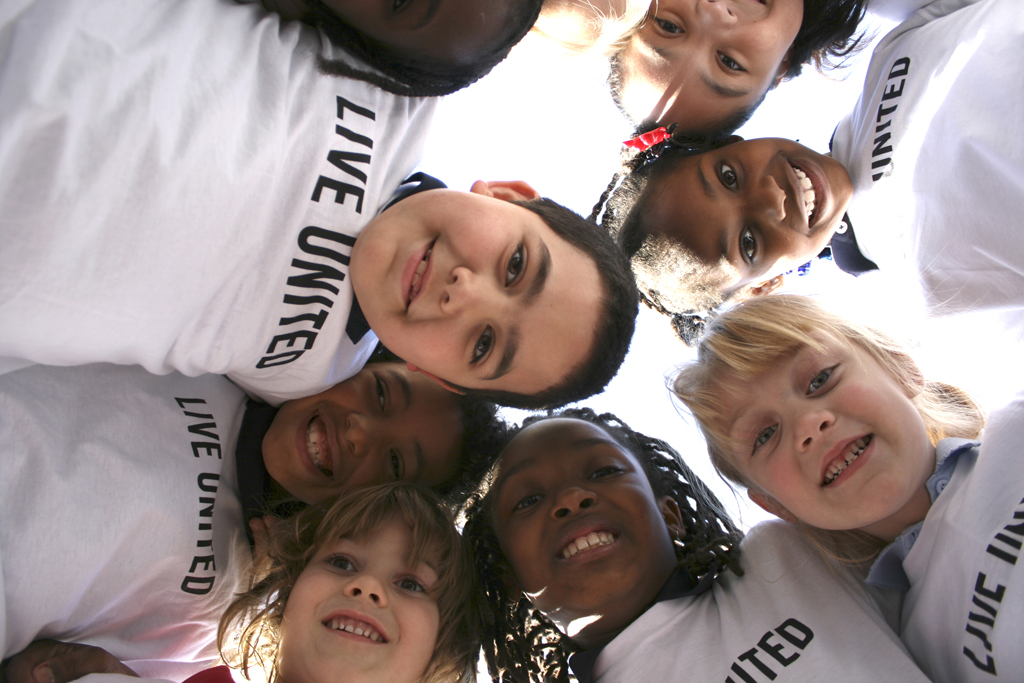 Kids huddle wearing Live United tshirts.