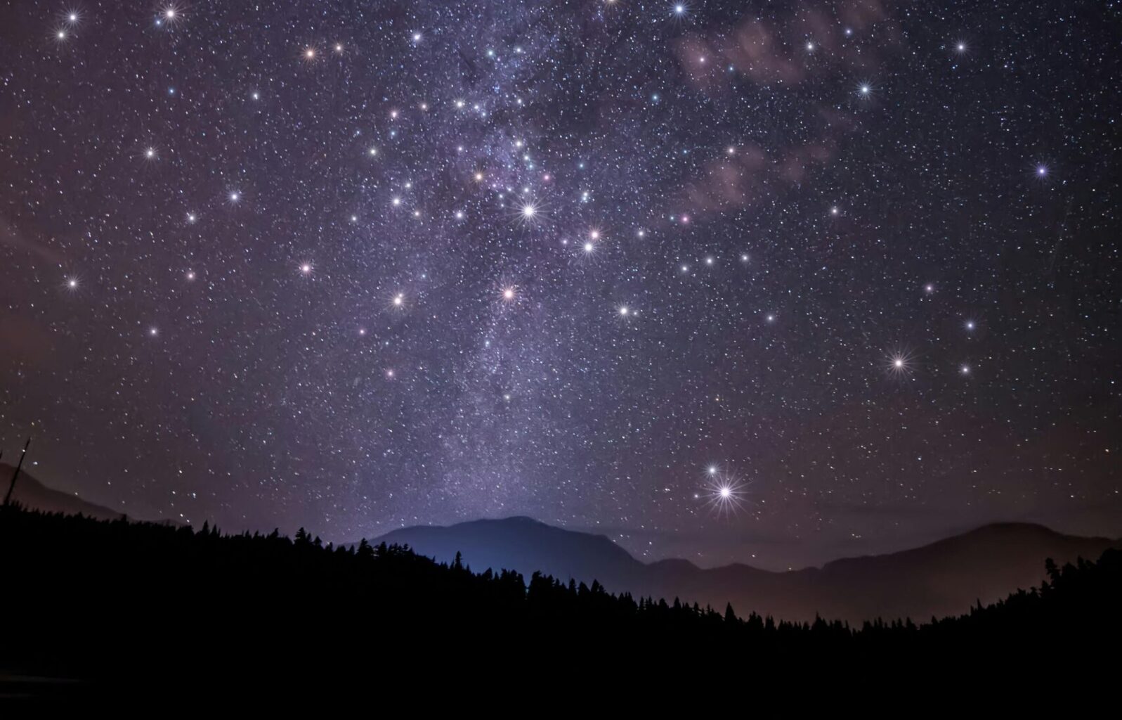 Starry night sky with mountains.