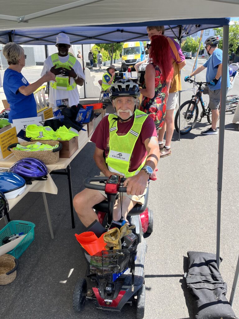 Man wearing a high visiblity vest on motor scooter during Medford Open Streets