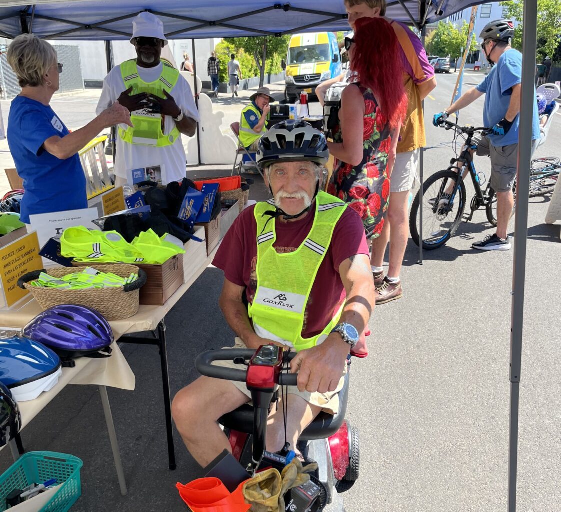 Man wearing a high visiblity vest on motor scooter during Medford Open Streets