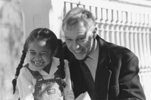 a man and young child with braids smiling.
